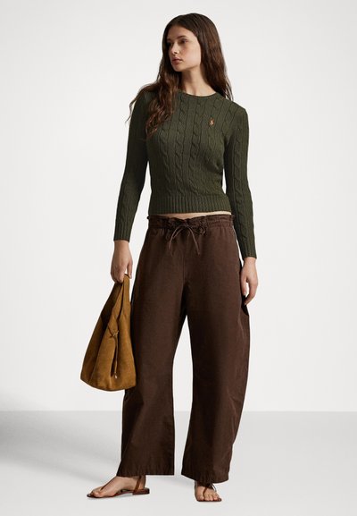 Alyvuogių žalumos kardiganas su apvalia iškirpte, derinamas su laisvais rudos spalvos kelnėmis ir rusvos spalvos zomšine rankine. Paprastus butus sandalai užbaigia įvaizdį.