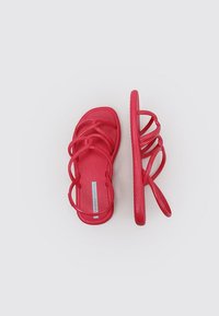 Sandalias de plástico rojo con múltiples correas delgadas, plantilla texturizada, suela plana y diseño minimalista, vistas desde arriba y de lado.