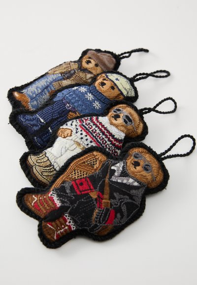 Set od četiri vezena privjeska u obliku medvjedića. Sadrži različite uzorke odjeće, boje poput plave, bijele, crvene i smeđe, s izvezenim detaljima.