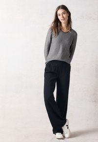 Grårandig tröja, svarta vida byxor och vita sneakers med svarta accenter. Enkelt mönster och mjuka material.