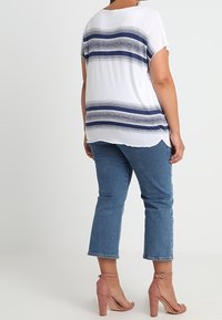 Top blanco de manga corta con rayas horizontales azul marino, combinado con jeans cortos azules y tacones de tira en tono rosa claro.