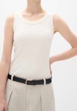 White ribbed tank top with a rounded neckline, paired with light beige linen trousers and a black leather belt featuring a gold buckle.