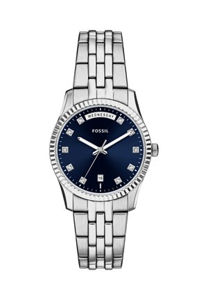 Orologio in acciaio inossidabile argentato con quadrante blu, indici orari simili a diamanti e datario. Caratterizzato da un bracciale a maglie e una lunetta zigrinata.