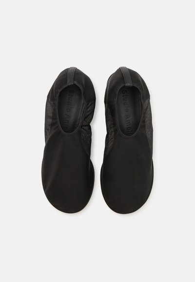 Scarpe nere slip-on con una tomaia in rete morbida e leggera. Punta arrotondata, superficie liscia e dettagli elastici alle aperture.