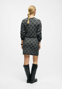 Robes en tricot grises avec motif en losanges, poignets et ceinture côtelés, associées à des bottes en cuir noir jusqu'aux genoux.