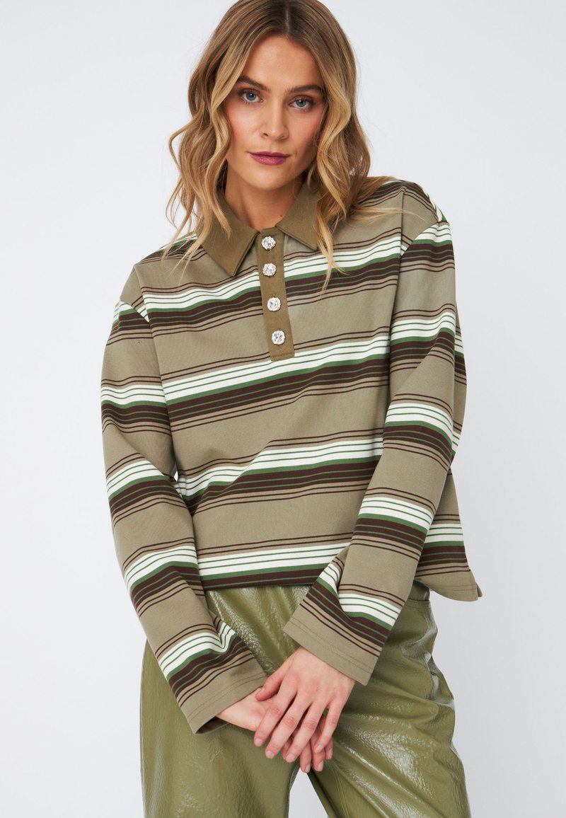 Polo-shirt à rayures marron et vert à manches longues avec un col, comportant cinq boutons décoratifs et un tissu texturé. Associé à un pantalon vert brillant.
