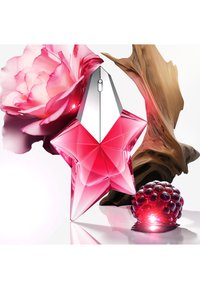 Frasco de perfume en forma de estrella de color rosa con una tapa metálica plateada, rodeado de una flor de peonía y acentos de madera texturizada, con detalles de frambuesa roja.