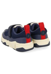 Zapatillas de malla azules con acentos rojos y blancos, que cuentan con una correa de gancho y bucle y una suela blanca gruesa y texturizada.