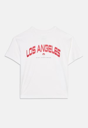 Biała koszulka z krótkim rękawem z czerwonym napisem "LOS ANGELES" i małym logo Nike Sportswear poniżej na przodzie.