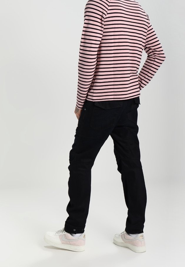 Gestreiftes langärmeliges Hemd in Pink und Schwarz, kombiniert mit schwarzen Hosen und weißen Sneakers mit pinken Akzenten. Legere Kleidung aus der Rückansicht.