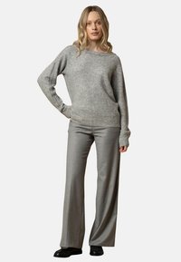 Maglione leggero grigio chiaro, lavorato a maglia con dettagli a coste, abbinato a pantaloni grigio chiaro. L'outfit presenta una vestibilità comoda e maniche lunghe.