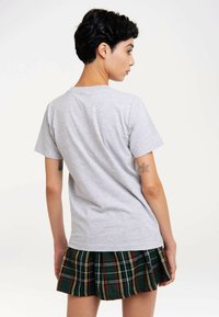 Gray short-sleeve t-shirt, cotton material, regular fit, plain design. Paired with a green plaid pleated skirt featuring red and yellow stripes.