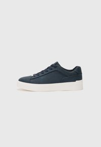 Tenis azul escuro com um cabedal de couro liso, bico redondo, frente com atacadores, sola de borracha branca e uma marcação subtil na lateral.