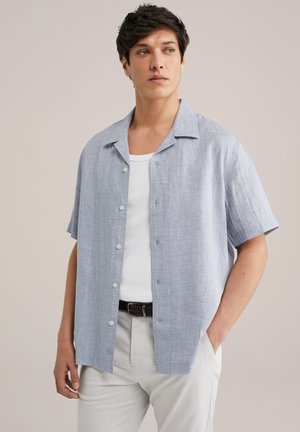 Blue and white short-sleeve button-up shirt with a collared design, featuring a textured fabric and a relaxed fit. Paired with a white tank top.