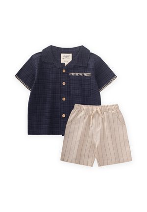 Navy checkered short-sleeve shirt with wooden buttons and pocket; beige shorts with vertical stripes and drawstring waist.