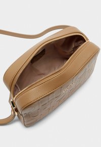 Borsa a tracolla in pelle tan con motivo in rilievo, zip dorata e interno liscio. Spallaccio regolabile per maggiore versatilità.