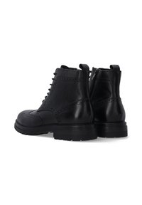 Černé kožené kotníkové boty s brogue designem, šněrováním vpředu a zipem, s robustní podrážkou a hladkým povrchem.