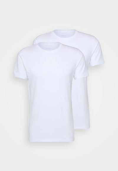Divas baltas kokvilnas t-krekli ar īsām piedurknēm, apaļām dekoltē un standarta piegriezumu. Gluda tekstūra, bez redzamām rakstu vai rotājumiem.