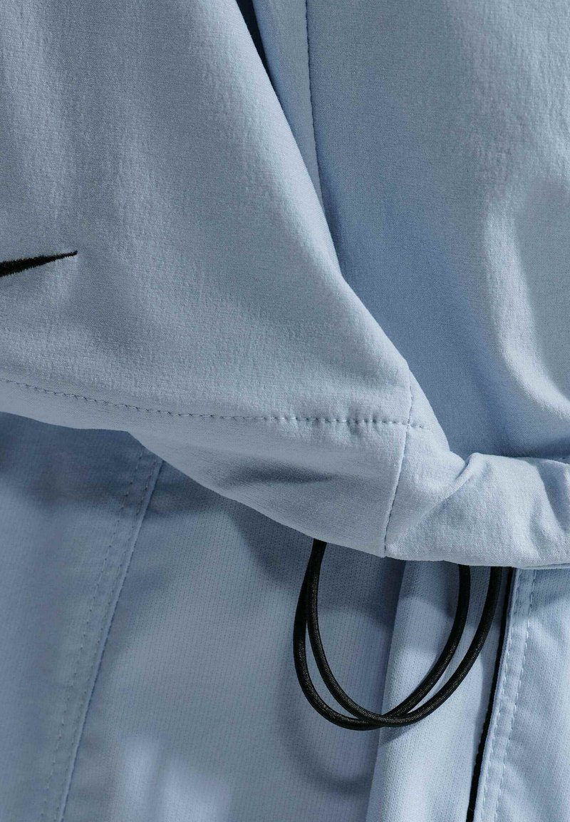Hellblauer Stoff mit schwarzen elastischen Kordeln, die detaillierte Nähte und Falten zeigen.
