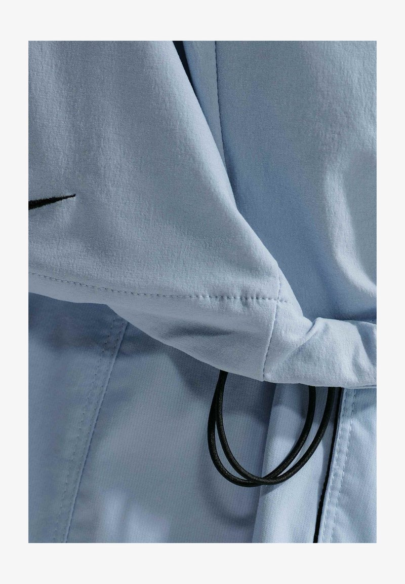 Tessuto azzurro chiaro con coulisse elastiche nere, che mostra cuciture e pieghe dettagliate.