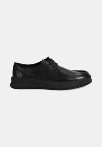 Schwarze Lederschuhe mit abgerundeter Zehenpartie, Schnürdesign und strukturierten Gummisohlen. Glatte Oberfläche mit Nahtdetails entlang der Kanten.