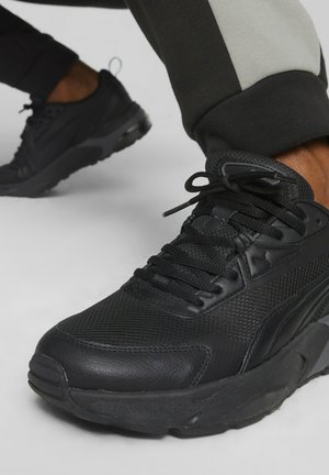 Scarpa sportiva nera con una tomaia in mesh testurizzata, linguetta imbottita e suola di gomma. I lacci sono neri, con un sottile dettaglio del logo sul lato.