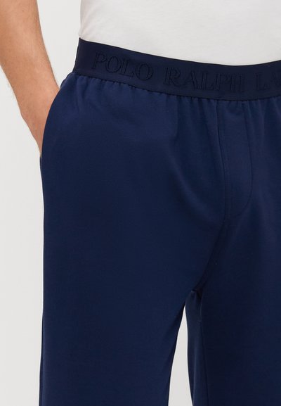 Mornarsko plave trenirke s elastičnim pojasom, sa izvezenim natpisom "POLO RALPH LAUREN" u usklađenoj nijansi; mekani materijal, opušteni kroj.