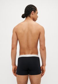 Boxers noirs avec une ceinture blanche portant le logo "Copenhagen Studios". Tissu doux et design ajusté.
