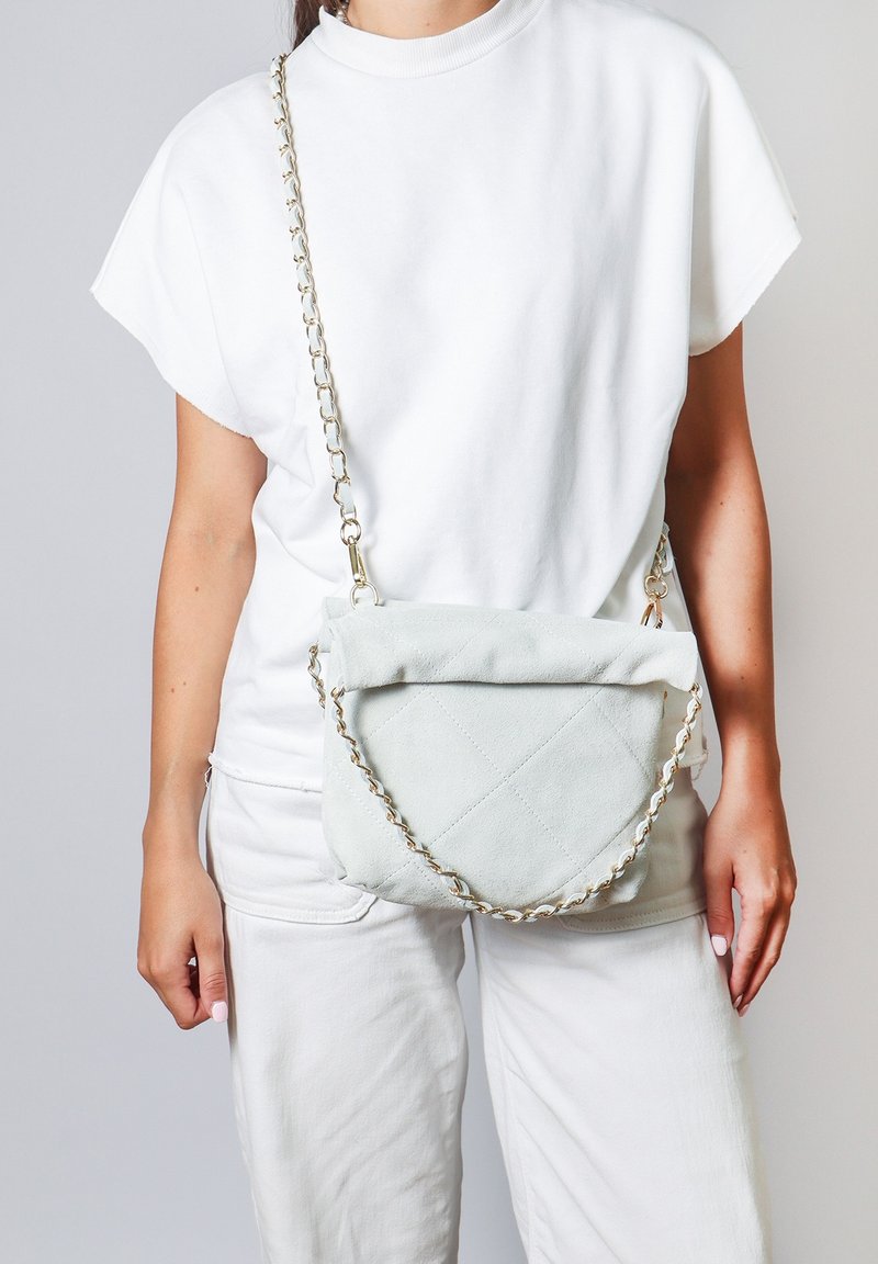 Borsa a tracolla in suede blu chiaro con design trapuntato, dotata di una tracolla a catena e una chiusura superiore piegata. Indossata in stile crossbody.