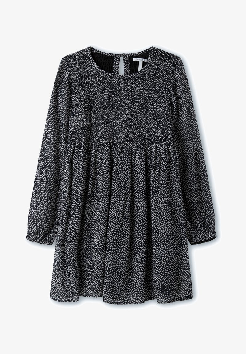 Vestido en blanco y negro con mangas largas, cintura fruncida, escote redondo y espalda con abertura. Presenta un patrón moteado y una tela suave.