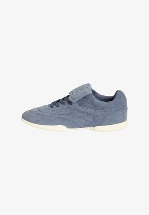 Blauwe suède sneaker met witte zool, vetersluiting en een gestikte klep over de veters op een effen witte achtergrond.
