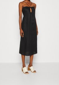 Svart linn midi-klänning med en nyckelhålsklippning framtill och tunna axelremmar. Matchad med beige blockklackssandaletter med en texturerad yta.