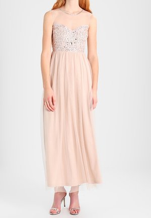 Abito lungo di un rosa chiaro con un corpo trasparente decorato con ricami argentati, presenta una gonna in tulle fluente e sottili spalline.