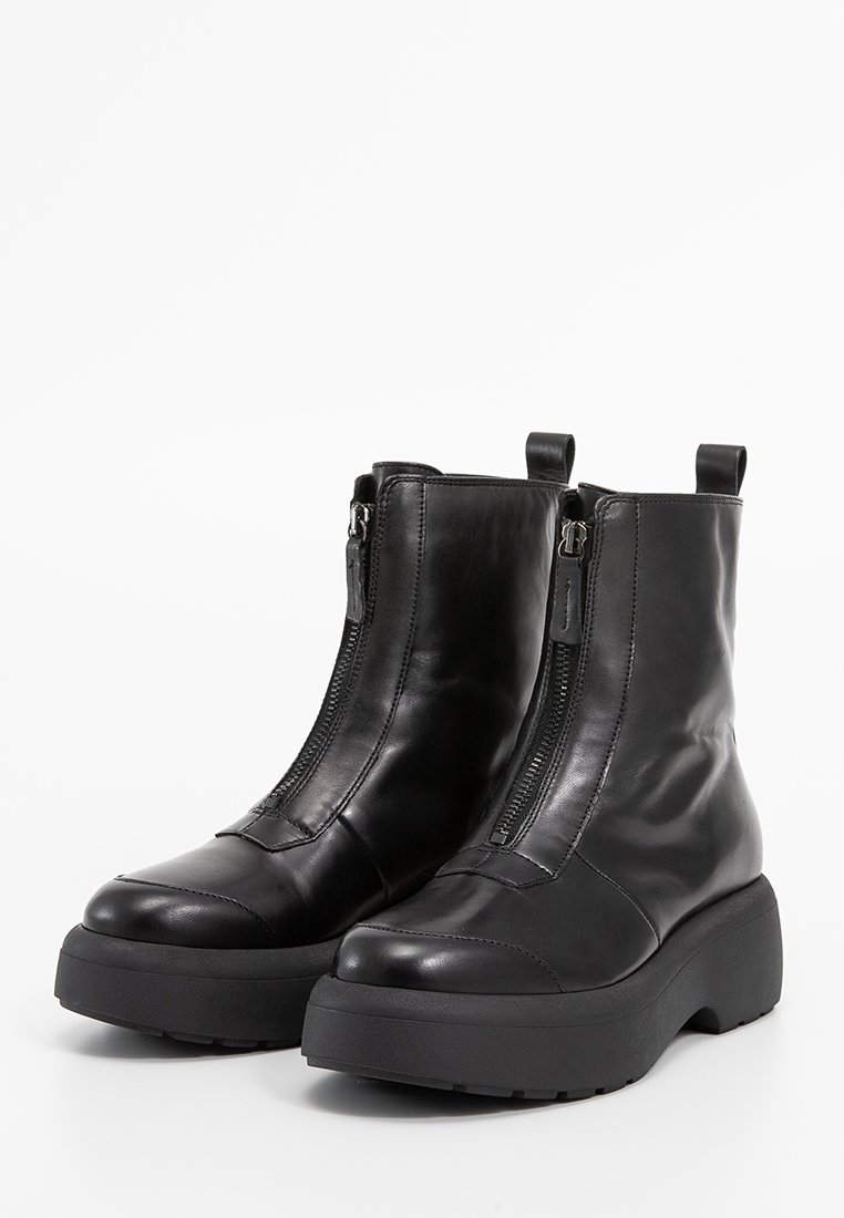 Schwarze Leder-Ankle Boots mit doppelten seitlichen Reißverschlüssen, abgerundeten Zehen und dickem Plattformsohlen. Glatte Textur mit minimalen Nähdetails.