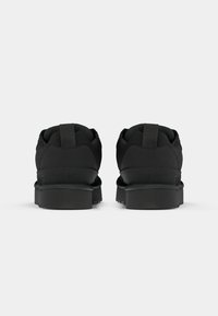 Black sneakers with a mesh upper, textured accents, and flat rubber soles. Features a pull tab at the heel for ease of wear.