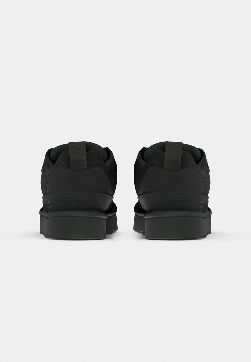 Zapatillas negras con parte superior de malla, acentos texturizados y suelas de goma planas. Cuenta con una lengüeta en el talón para facilitar su colocación.