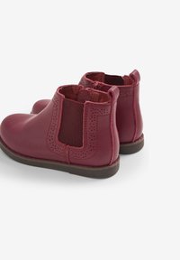 Botas de tobillo de cuero burdeos con paneles laterales elásticos, diseño perforado, punta redondeada y suelas planas para mayor comodidad y facilidad de uso.