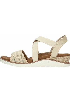 Sandalias de cuña beige con correas elásticas cruzadas, parte superior de tela texturizada, plantilla acolchada marrón y detalle de tacón envuelto en cuerda.
