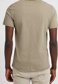 Camiseta de manga corta y cuello redondo en algodón color caqui claro, con un diseño liso y corte ajustado, y detalles de costura sutiles en las mangas.