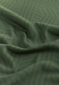 Tissu vert avec des motifs géométriques en zigzag subtils et des plis doux créant texture et profondeur.