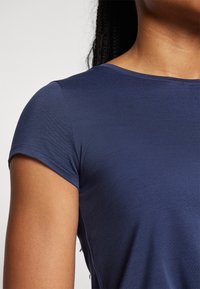 Camiseta de manga corta en color azul marino, hecha de una tela suave. Presenta un cuello redondeado y un ligero estiramiento, con costuras sutiles a los lados.