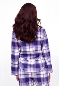 Fioletowy, w kratę zestaw piżamowy składający się z długich rękawów, koszuli z kołnierzykiem oraz dopasowanych spodni o miękkiej fakturze i zaokrąglonych brzegach.