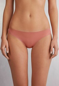 Staubig rosa nahtloser Bikini mit minimalistischem Design. Hergestellt aus weichem, glattem Stoff, mit einem tiefen Schnitt und breiten Bündchen.
