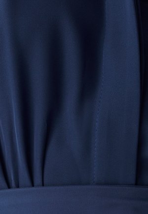 Tamsiai mėlynas audinys su lygiu paviršiumi, turintis subtilius raukšles ir tvarkingus siūlus. Dizainas yra struktūruotas su prigludusia liemenėle.