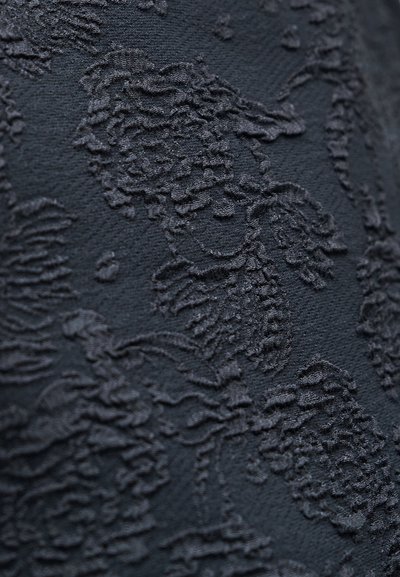 Material negru texturat cu un model ondulat și reliefat. Textura pare moale și realizată cu atenție, adăugând profunzime și detaliu.