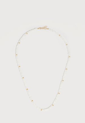 Delikati kaklo grandinėlė su mažais baltais karoliukais ir tolygiai išdėstytais auksiniais akcentais, su auksine užsegimu ir reguliuojamu grandinėlės ilgiu, ant paprasto fondo.