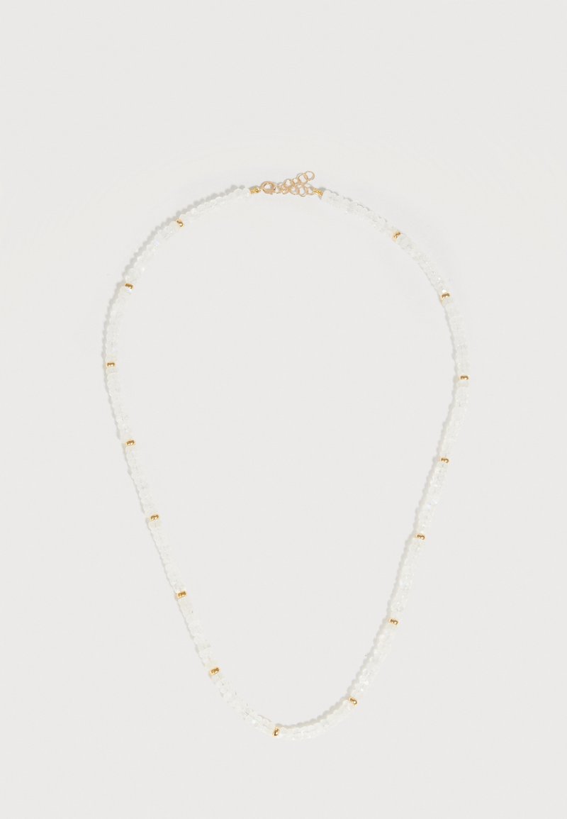 Λεπτό κολιέ με μικρές λευκές χάντρες και ομοιόμορφα τοποθετημένες χρυσές λεπτομέρειες, με χρυσή κλειδαριά και ρυθμιζόμενη αλυσίδα σε απλό φόντο.