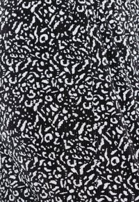 Czarna tkanina z białym abstrakcyjnym wzorem, z teksturowanym prążkowaniem. Wzór obejmuje różne płynne kształty i linie rozproszone w całej tkaninie.
