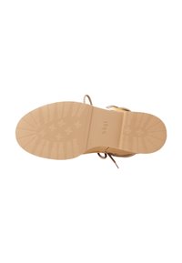 Beige schoeisel met een gladde textuur, voorzien van een patroon onder de zool en een kleine hak. Inclusief een dunne veterdetail aan de zijkant.