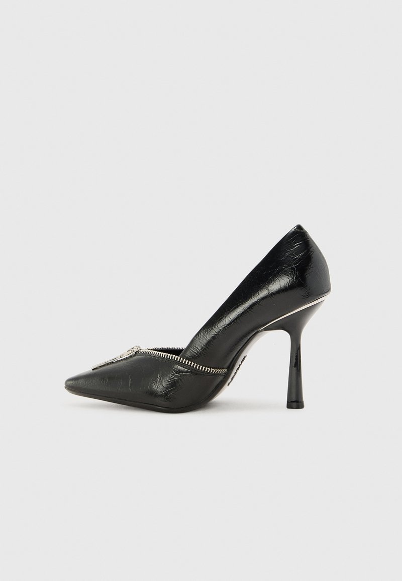 Chaussure à talon haut noire avec bout pointu, matière texturée brillante et détail de fermeture éclair argentée sur le côté avant.